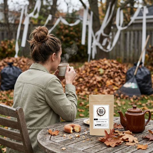 woman looking at her yard full of leaves and toilet paper wrapped trees sipping a cup of apple cider rooibos loose leaf tea with a teapot on the table, a tea bag, and a partially eaten donut. 